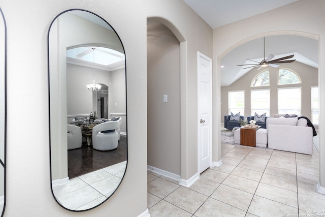 hallway featuring light tile patterned floors, vaulted ceiling, a chandelier, and baseboards