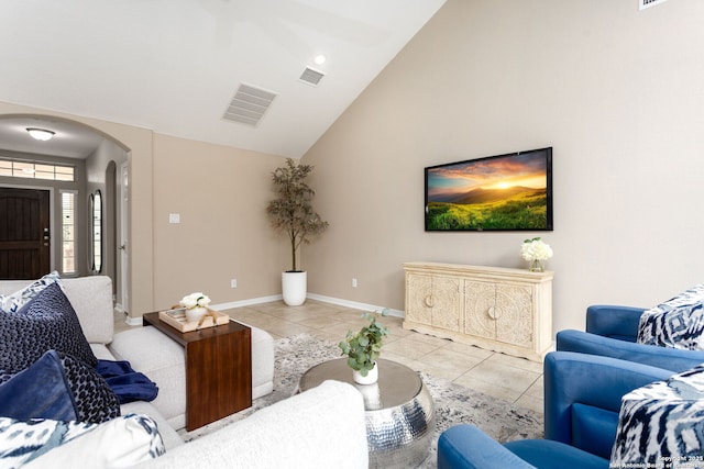 living area with arched walkways, light tile patterned floors, visible vents, and baseboards