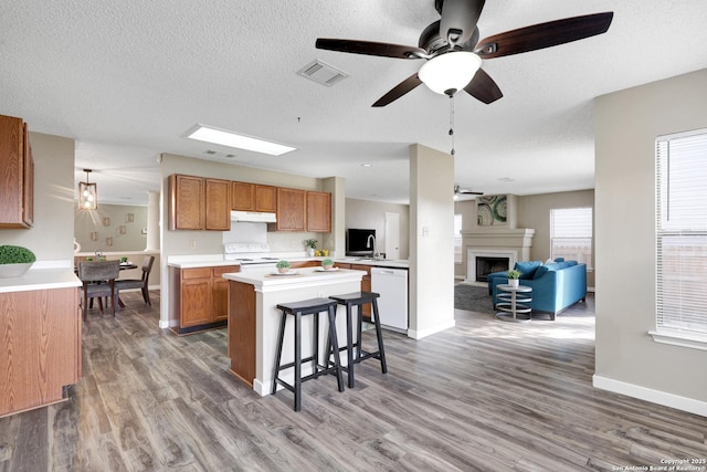 kitchen featuring white appliances, open floor plan, light countertops, hanging light fixtures, and brown cabinets