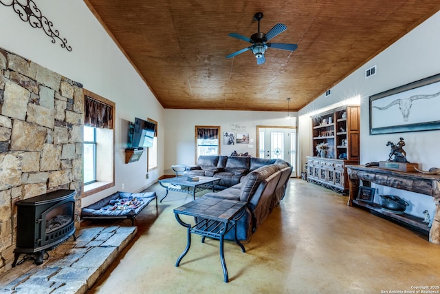 living area featuring finished concrete flooring, a wood stove, wood ceiling, and a ceiling fan