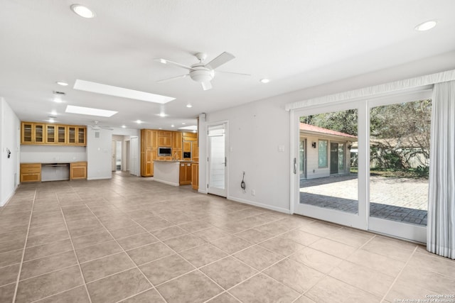 unfurnished living room featuring a skylight, light tile patterned floors, baseboards, a ceiling fan, and recessed lighting