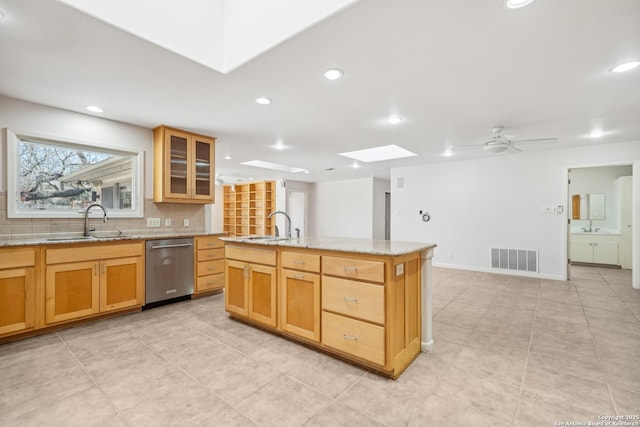 kitchen featuring a skylight, visible vents, dishwasher, backsplash, and a sink