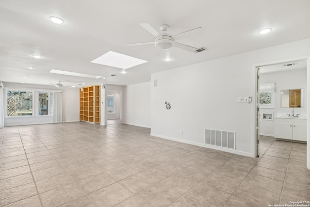 unfurnished living room featuring a skylight, visible vents, and a ceiling fan