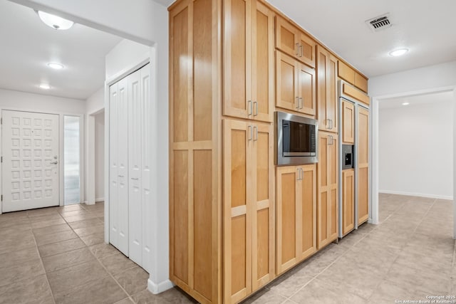 kitchen featuring built in appliances, light tile patterned floors, visible vents, and baseboards