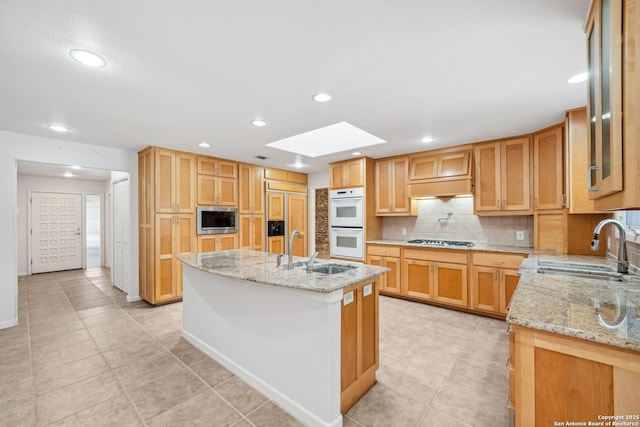 kitchen with built in appliances, tasteful backsplash, a skylight, and a sink