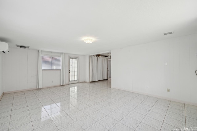 empty room featuring light tile patterned flooring, visible vents, and a wall mounted AC