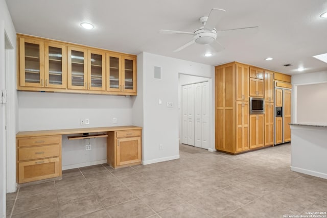 kitchen featuring visible vents, a ceiling fan, glass insert cabinets, built in study area, and built in appliances