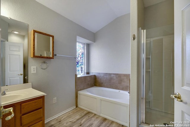 bathroom with lofted ceiling, a stall shower, vanity, wood finished floors, and a bath