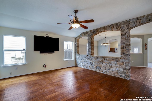 unfurnished living room featuring ceiling fan with notable chandelier, lofted ceiling, arched walkways, and wood finished floors