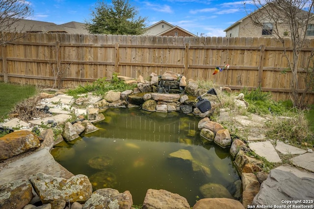 view of yard featuring fence and a garden pond