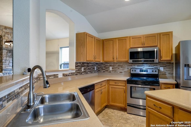 kitchen with appliances with stainless steel finishes, light countertops, a sink, and tasteful backsplash