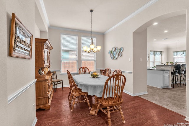 dining space featuring dark wood-style floors, arched walkways, crown molding, and a notable chandelier