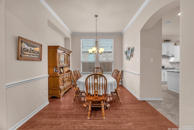 dining space featuring arched walkways, crown molding, visible vents, an inviting chandelier, and baseboards