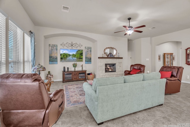 living room featuring a ceiling fan, visible vents, a fireplace, and baseboards