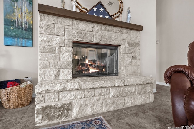 room details featuring a stone fireplace, visible vents, and baseboards