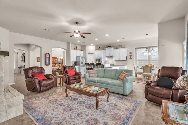 living room featuring arched walkways, light tile patterned floors, recessed lighting, ceiling fan with notable chandelier, and visible vents