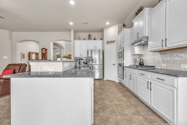 kitchen with a center island with sink, white cabinets, appliances with stainless steel finishes, open floor plan, and under cabinet range hood