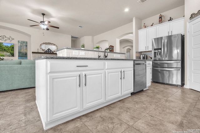 kitchen with stainless steel appliances, open floor plan, white cabinets, and a center island with sink