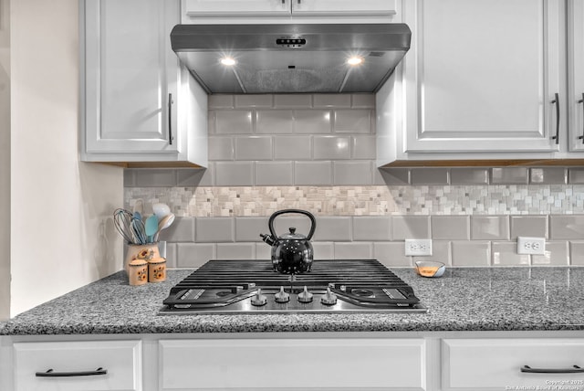 kitchen featuring white cabinets, decorative backsplash, dark stone countertops, ventilation hood, and stainless steel gas stovetop