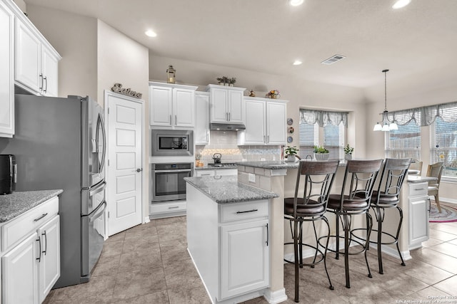 kitchen featuring decorative light fixtures, stainless steel appliances, visible vents, white cabinetry, and a kitchen island