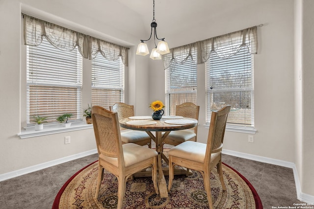 dining area featuring dark tile patterned floors, baseboards, and a chandelier