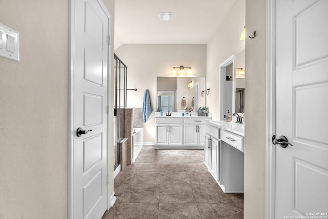 full bath featuring tile patterned flooring, double vanity, a sink, and a bath