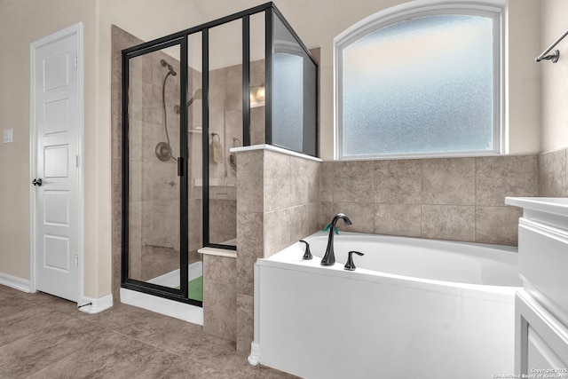 bathroom with a stall shower, a bath, and tile patterned floors