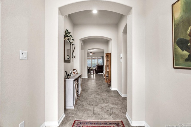 hallway featuring arched walkways and baseboards