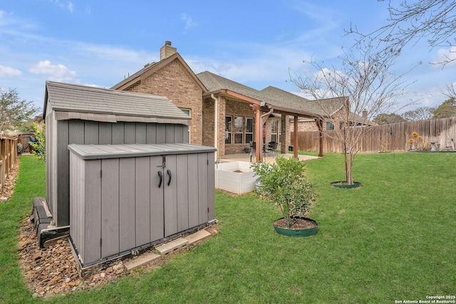 view of yard with ceiling fan, a fenced backyard, an outdoor structure, a shed, and a patio area