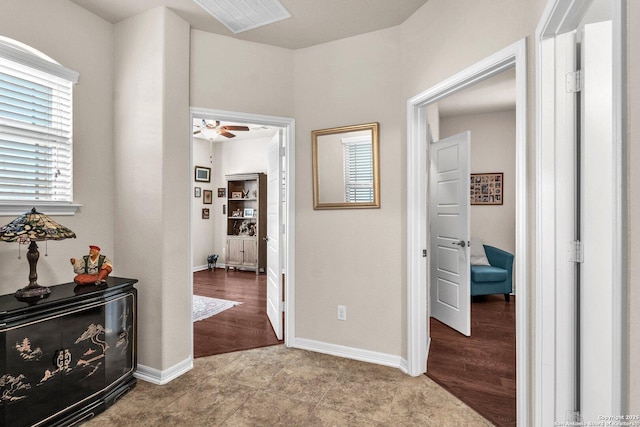 corridor with light wood finished floors, visible vents, and baseboards