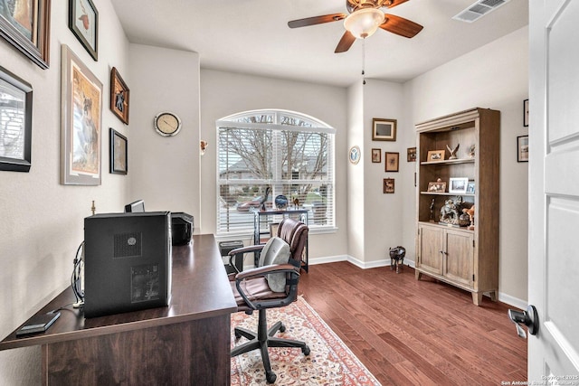 office space with a ceiling fan, visible vents, baseboards, and wood finished floors