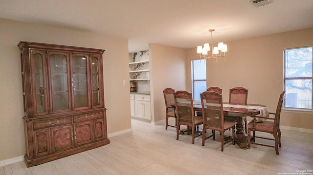 dining area featuring light wood-style flooring, visible vents, a chandelier, and baseboards