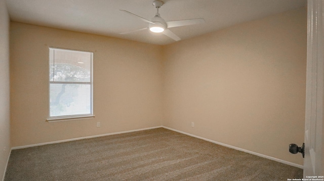 carpeted spare room featuring baseboards and a ceiling fan