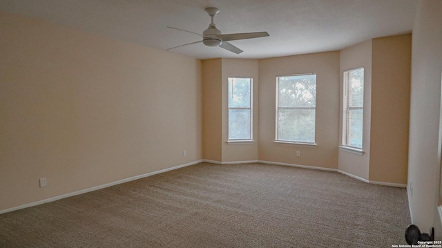 spare room with a ceiling fan, light colored carpet, and baseboards