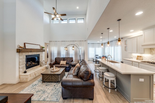 living room featuring recessed lighting, a fireplace, light wood-style flooring, and a ceiling fan