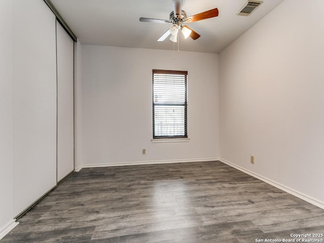 unfurnished room with dark wood-type flooring, visible vents, ceiling fan, and baseboards