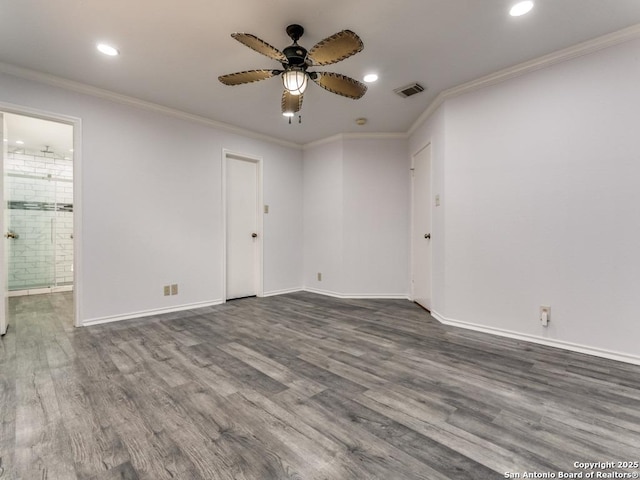 empty room with ceiling fan, visible vents, dark wood finished floors, and ornamental molding