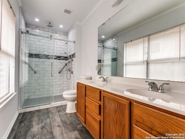 full bathroom with crown molding, double vanity, a sink, a shower stall, and wood finished floors