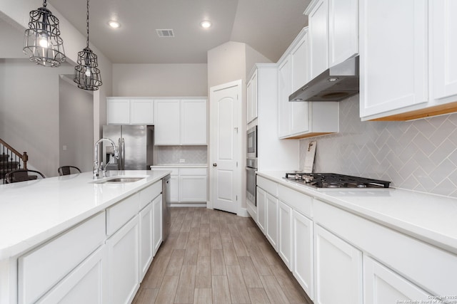 kitchen with range hood, light countertops, hanging light fixtures, and white cabinetry