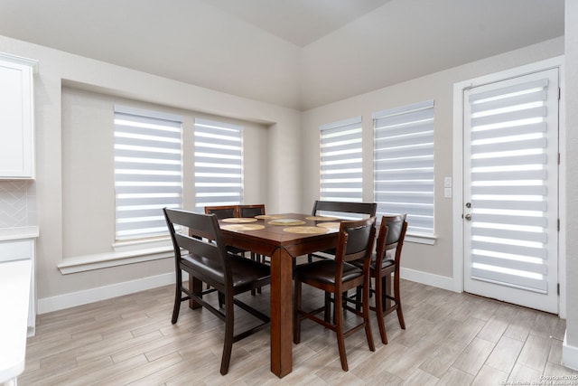 dining area with lofted ceiling, baseboards, and wood finish floors