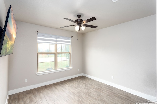 empty room with ceiling fan, light wood-style flooring, and baseboards