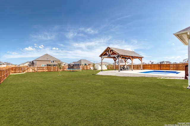 view of yard featuring a trampoline, a fenced backyard, a patio, and a gazebo