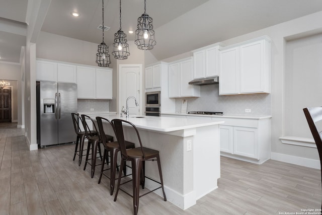 kitchen featuring appliances with stainless steel finishes, light countertops, a kitchen island with sink, and white cabinetry