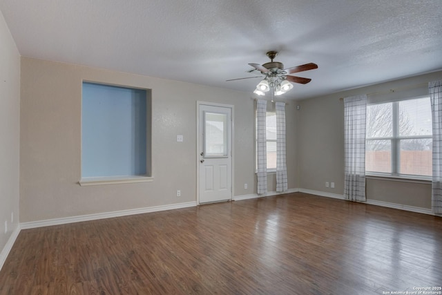 unfurnished room with a textured ceiling, ceiling fan, dark wood finished floors, and baseboards