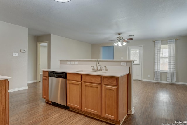 kitchen featuring a sink, light wood finished floors, light countertops, and dishwasher