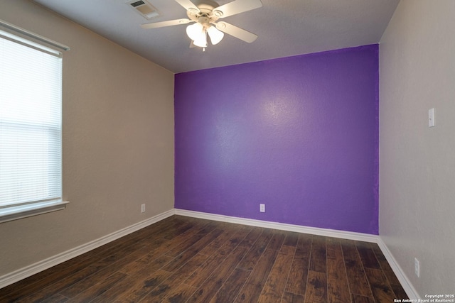 unfurnished room featuring dark wood-style floors, baseboards, visible vents, and a ceiling fan