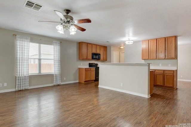 kitchen featuring black appliances, light countertops, visible vents, and brown cabinets