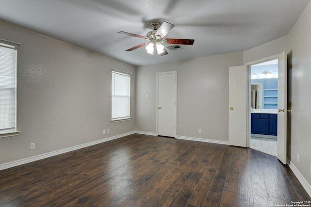 empty room with dark wood-style floors, baseboards, visible vents, and a ceiling fan