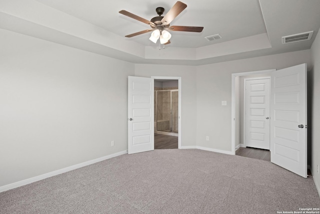 unfurnished bedroom featuring carpet floors, a raised ceiling, and visible vents