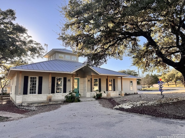 view of front of home featuring stone siding, a standing seam roof, metal roof, and a porch